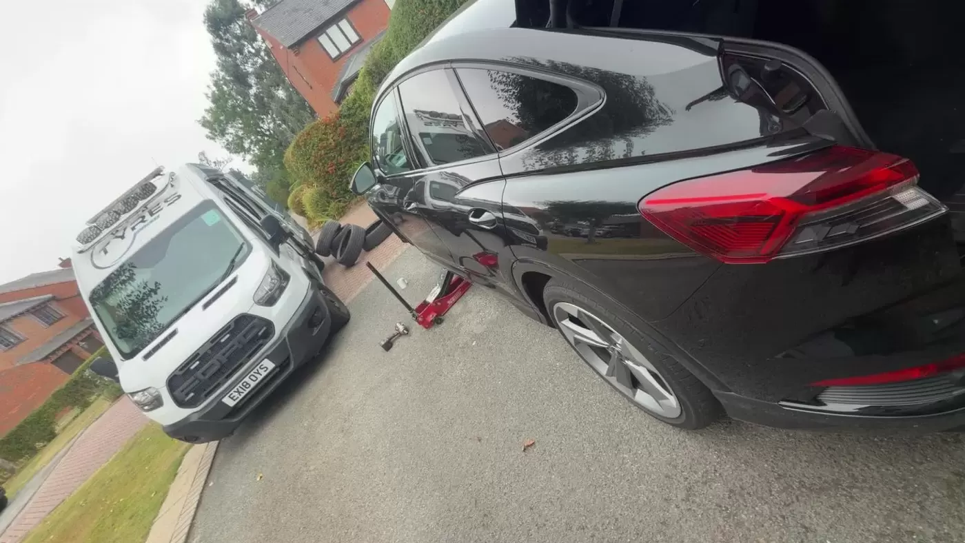 Black car raised for mobile tyre fitting at the roadside